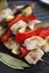 Closeup of baked greek fish souvlaki with cod, red bell pepper, lemon and bay leaves, selective focus