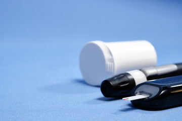The glucometer with the test strip on a blue background. space for text. selective focus