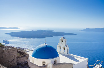 A blue domed church with bell tower and view of calderain in Fira, Santorini,  Cyclades, Greece