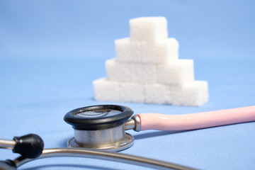 Pink stethoscope, sugar cubes on a blue background, diabetes. Space for text, selective focus