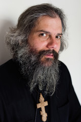 Close-up portrait face of a middle-aged Orthodox priest monk man with a beard looking at the camera
