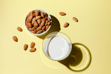 Almond milk in a glass on yellow background - alternative dairy