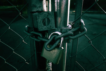 Locked Gate Tethered by metal chain and old rusty padlock on dark background. - Powered by Adobe