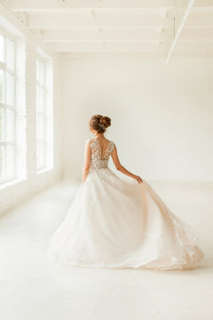 bride in white dress. young woman in wedding dress in white room. 
