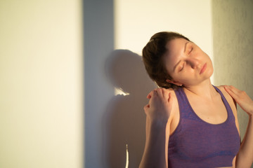 Fototapeta na wymiar A young woman is stretching her neck at sunset or dawn. Exercise for health and well-being
