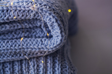 Background or texture of blue hand-knitted plaid and pillows in cosy autumn or winter home.