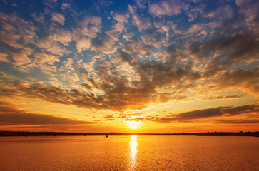 Fototapeta na wymiar Beautiful sunset on the lake with clouds and reflections on the water
