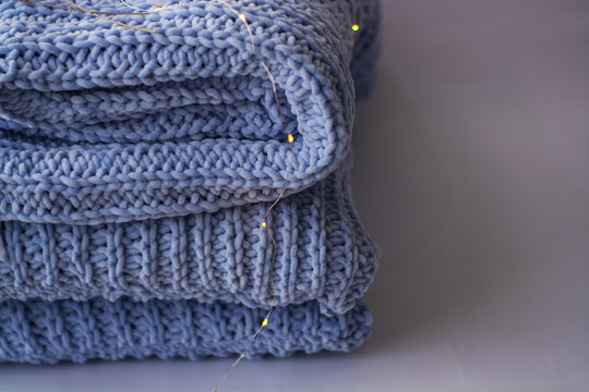 Background or texture of blue hand-knitted plaid and pillows in cosy autumn or winter home.