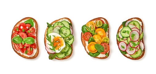 Open sandwiches with vegetables cherry tomato, cucumber, radish. Italian vegan bruschetta with soft cheese. Various sandwich with spinach isolated on white background, top view. Flat lay
