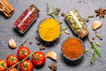 Fresh organic spices and herbs on dark stone background top view. Traditional Indian spices on the table.