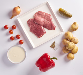 Delivery of packaged food for dinner. meat in plactic bag and vegetables: potatoes, onions, spices, cherry tomatoes, red pepper