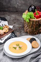 Cream soup with salmon in a white plate on dark concrete background