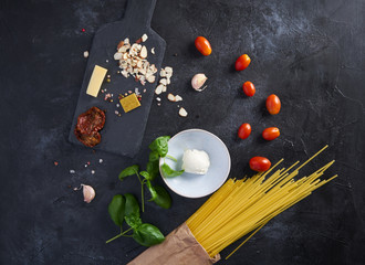 A set of products for an Italian dinner: spaghetti pasta, cherry tomatoes, basil, garlic, cream cheese on a black textured background. Dinner Set Food Delivery