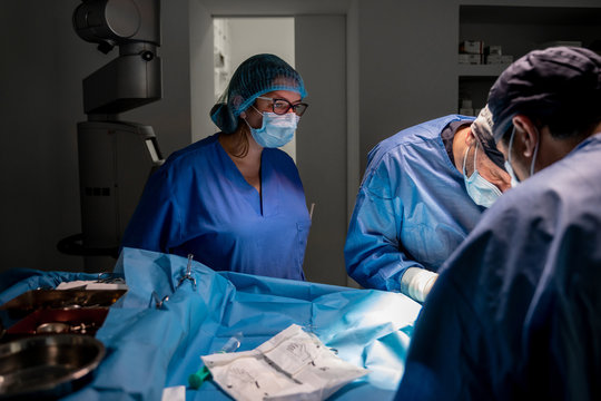 Surgeons and nurses in uniform concentrating and operating patient using special equipment in operating room of contemporary hospital