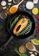 Salmon steak in a grill pan with spices on a dark table. Seafood. Cooking concept. Culinary background. Flat lay.