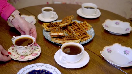 Woman arranges cups and saucers on the table. Dinner with tea and coffee.