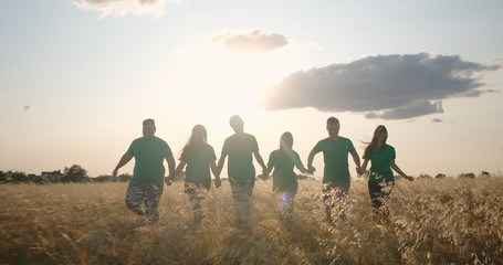 Group of boys and girls walking together hand in hand in the field. The concept of peace,...