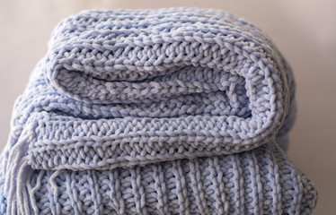 Background or texture of blue hand-knitted plaid and pillows in cosy autumn or winter home.
