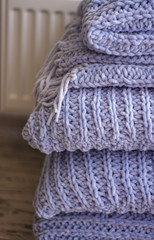Background or texture of blue hand-knitted plaid and pillows in cosy autumn or winter home.