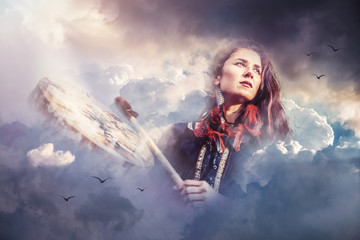 beautiful shamanic girl playing on shaman frame drum in the cloud.