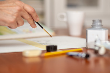 woman hand holding a brush with watercolor. Shallow depth of field