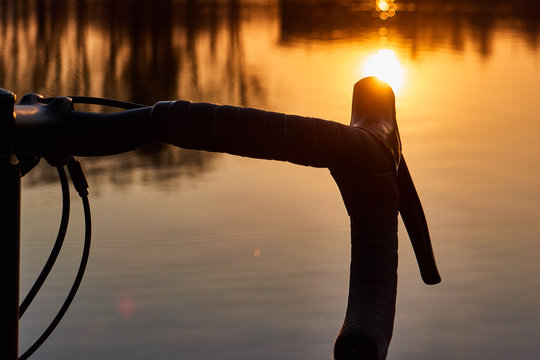 bicycle near lake, steering wheel over water on sunset background ,gravel bike close up