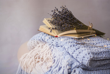 Background of blue hand-knit plaid and pillows in cosy home with dried bouquet of lavender flowers,...