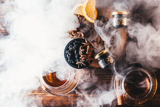 Hookah tobacco in the clay bowl with cinnamon and anise stars, with thick smoke cloud around, top view shot with oriental vibe