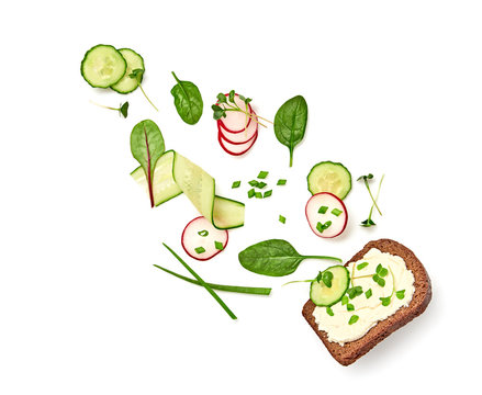 Open sandwich radish, cucumber, soft cheese flying. Vegan sandwich with rye bread, microgreen isolated on white, top view. Levitation fly diet smorrebrod creative cook concept