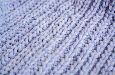 Background or texture of blue hand-knitted plaid and pillows in cosy autumn or winter home.