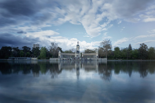 Architectural ensemble of monument to Alfonso XII on waterfront of calm quiet pond in park