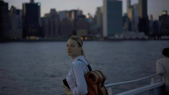 Beautiful tourist 20 years old with stylish backpack enjoying voyage trip for exploring Manhattan island from water boat, amateur photographer using vintage camera for making images of New York
