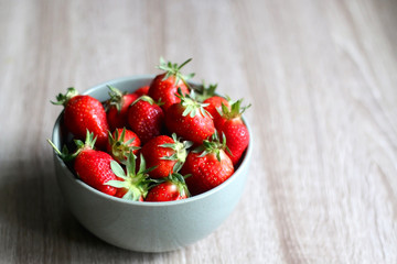 Bowl of fresh strawberries on wooden table. Selective focus.