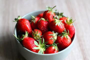Bowl of fresh strawberries on wooden table. Selective focus.
