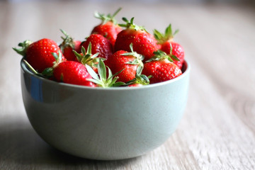 Bowl of fresh strawberries on wooden table. Selective focus.
