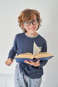 blond kid in pajamas with a book playing research