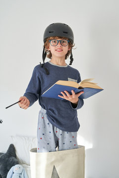 blond kid in pajamas with a helmet a flashlight and a book playing research