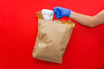 The delivery man's hand holds a paper bag with food. Donation, coronavirus quarantine.