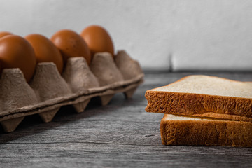 Close up bread and eggs is in paper trays put on wooden floor background and copy space for text