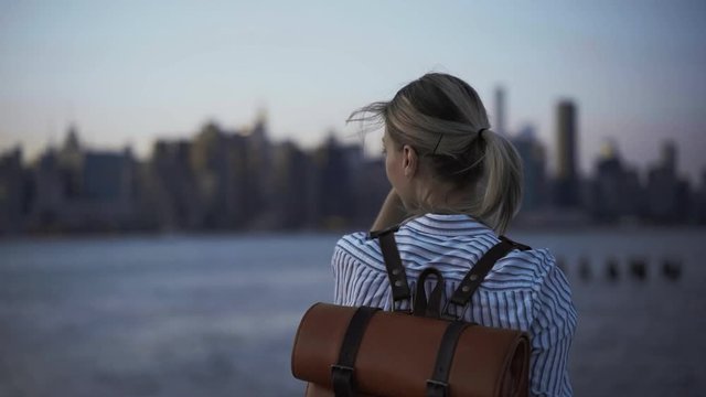 Millennial female tourist with trendy backpack spending time for voyage sightseeing in New York using smartphone camera for clicking pictures and share to social web networks
