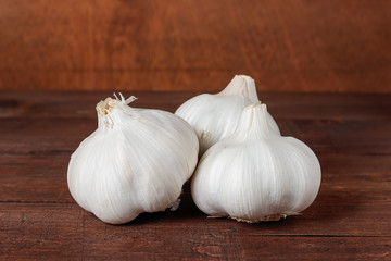 three garlic heads on a wooden table