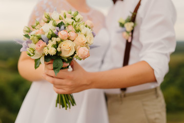 Obraz na płótnie Canvas bride and groom hold wedding bouquet in hands. Close-up. Wedding concept.