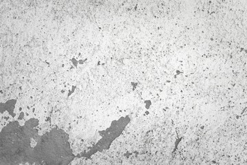 Weathered white wall. Peeling paint shows concrete underneath. Detail close up.