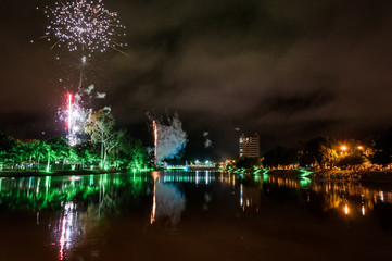 Colorful fireworks over Bebedouro city (SP state - Brazil) at night with reflection in the water