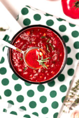 Spicy homemade tomato sauce with rosemary and garlic in a spoon on a table background, top view, selective focus