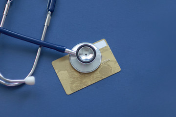 Stethoscope on Mock up Credit Card with number on cardholder in hospital desk. Health insurance and cost of care, self-care during illness using payments card for medicals service. Soft focus