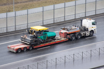 Trailer transportation paver truck on city highway.