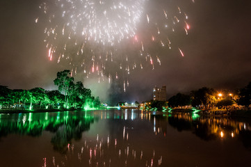 Colorful fireworks over Bebedouro city (SP state - Brazil) at night with reflection in the water