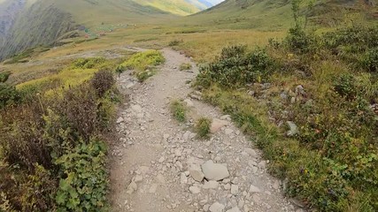 Point view from action camera biker riding freeride enduro on rocky downhill trail path in mountain. Bicyclist traveling on mtb stony route in highlands