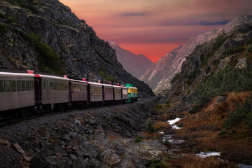 Old Historic Railroad Train is going over White Pass. Moody Colorful Sky Composite. Skagway,...
